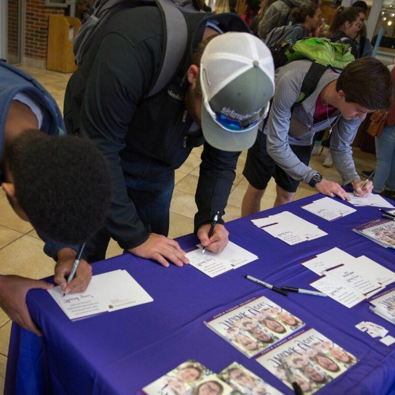 Students sign up at a fair.